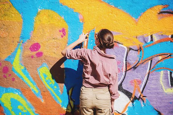 Junge Frau malt ein buntes Graffiti an eine Wand